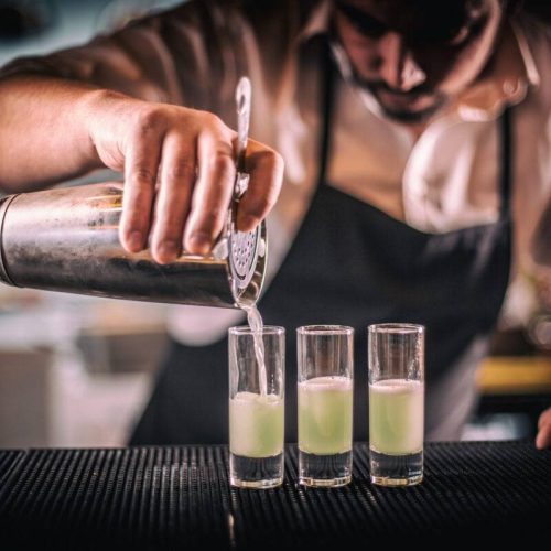 Bartender pouring fresh cocktail in short glass for service guest